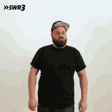 a man wearing a hat and a black shirt is standing with his eyes closed in front of a swr3 sign