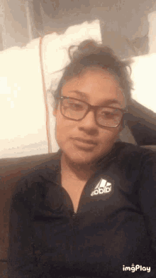 a woman wearing glasses is wearing an adidas shirt