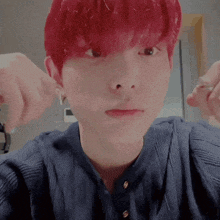 a young boy with red hair is wearing a blue shirt and earrings