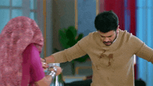 a man and a woman are standing next to each other in a room . the woman is wearing a hijab .