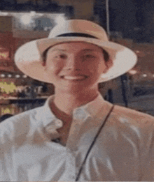a man wearing a white shirt and a hat is smiling .