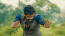 a man with blue hair and a beard is running in a field with his hands outstretched .