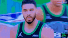 a basketball player wearing a green and black jersey with the word amicia on it