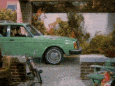 a green car is parked next to a bicycle