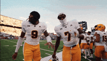 two football players one wearing number 9 and the other wearing number 7 walk off the field