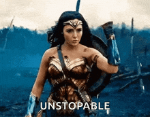 a woman in a wonder woman costume is holding a shield and a sword and says `` unstoppable '' .