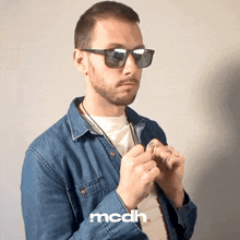 a man wearing sunglasses and a denim shirt with mcdh written on the bottom right