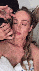 a woman with her eyes closed is getting her makeup applied