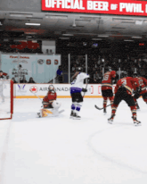 a hockey game is being played in front of an official beer sign