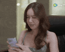 a woman is looking at her cell phone with a wetv logo in the background