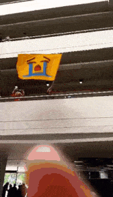 a yellow flag with a crying face on it hangs from a balcony