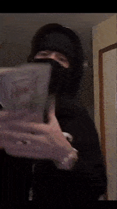 a man wearing a mask is holding a stack of money in his hands .