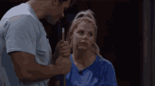 a man and a woman are standing next to each other in a dark room . the woman is wearing a blue shirt .