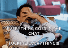 a man is sitting on a couch and covering his face with his hand with the words everything goes in the chat fucking everything