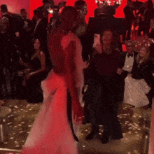 a woman taking a picture of a man in a white dress at a party