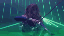 a woman is playing a violin in a dark room with green lights behind her