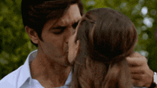 a man kisses a woman on the cheek in front of a green background