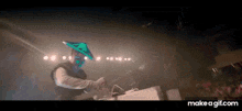 a man wearing a mask and a green hat is playing a dj set .