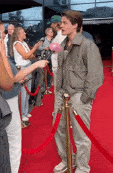 a man on a red carpet is being interviewed by a reporter