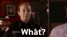 a woman in a police uniform is talking to a man in a room and asking him what .