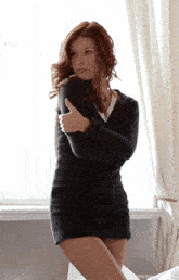 a woman in a short black dress is hugging herself