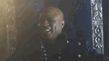 a bald man in a black jacket is smiling