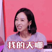 a woman in a blue shirt is smiling with chinese writing behind her
