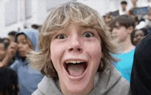 a young boy is making a funny face with his mouth open .