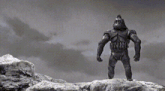a black and white photo of a statue of a gorilla standing on top of a rock .