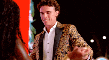 a man in a paisley jacket is holding a woman 's hand
