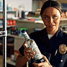 a woman in a police uniform is holding a bottle of black rifle