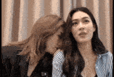 two women sitting next to each other with one wearing a striped shirt that says ' lg ' on it
