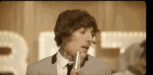 a man in a suit is singing into a microphone .