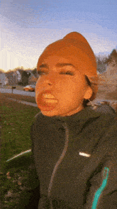 a woman wearing an orange beanie and a black jacket with the word lafuma on the sleeve
