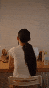 a woman sits at a desk with a ponytail