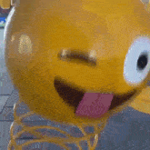 a yellow smiley face with a pink tongue sticking out is winking .
