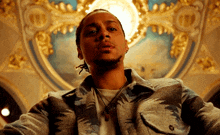 a man in a plaid jacket stands in front of a gold and blue ceiling