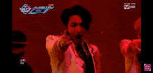 a man in a white suit and tie is standing in front of a microphone on a stage .