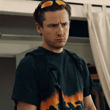 a man wearing sunglasses and a black shirt has a backpack