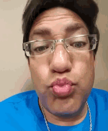 a man wearing glasses and a blue shirt making a funny face