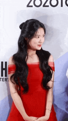 a woman in a red dress is standing in front of a sign that says zozoio