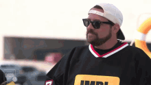 a man with a beard wearing sunglasses and a jersey that says imdb