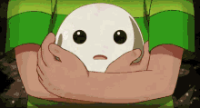 a person in a green shirt is holding a white object with a face on it