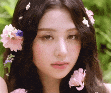 a close up of a woman 's face with pink flowers in her hair
