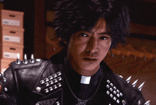 a man in a leather jacket with spikes and a cross on his chest