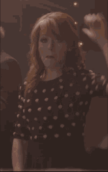 a woman with red hair wearing a black and white polka dot dress