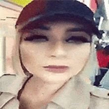 a woman wearing a baseball cap and a trench coat is looking at the camera .
