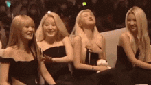 a group of women are sitting next to each other in a row in a crowd .