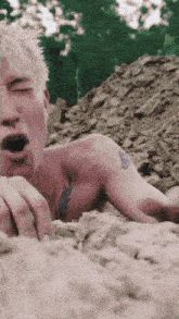 a shirtless man with a tattoo on his shoulder is laying on the ground