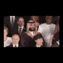 a man in a saudi arabian costume is standing in front of a group of people .